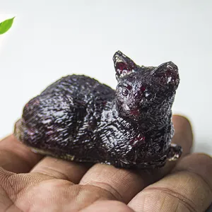 Mini figura de gato de resina con cristaux de granate rojo oscuro sostenida en mano