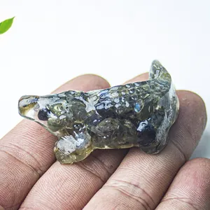 Detail of hand-held dark grey resin crocodile figurine with natural crystal textures