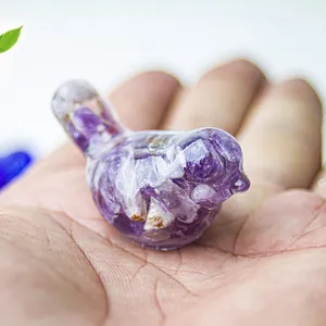 Bird statue crafted from transparent resin with natural amethyst crystals held in palm