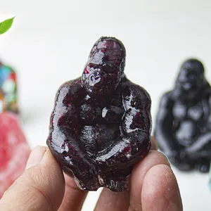 Detailed close-up of a carved dark red crystal gorilla statue held in hand for size