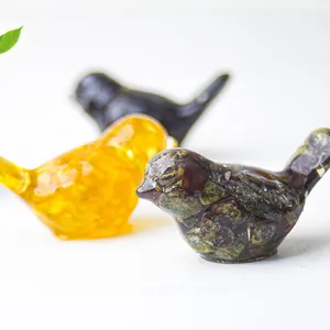 Detailed close-up of resin bird statues with crystal stones and gold foil accents