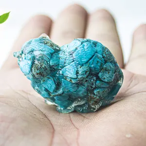 Artistic cat figurine made of blue-green natural crystal resin held in a hand