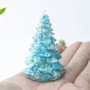 Mini sapin de Noël en résine et pierres turquoise tenu en main pour l'échelle