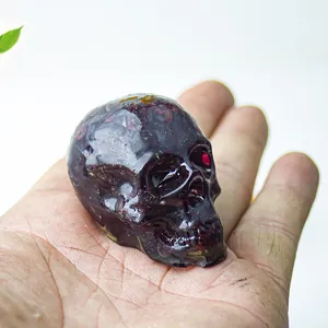 Macro view of a small resin skull figurine filled with natural purple crystal stones in hand