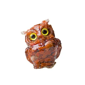 Resin owl figurine with natural red crystal stones and yellow eyes on white background