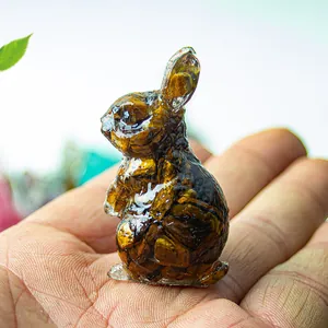 Vue rapprochée d'une figurine de lapin en œil de tigre tenue à la main pour l'échelle