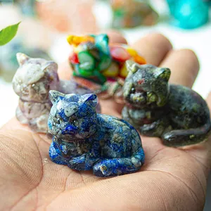 Macro shot of miniature resin cat figurines in various natural stones held in palm