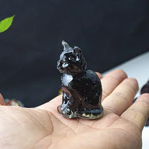 Miniature black resin lucky cat figurine held in hand to show the small size and high gloss