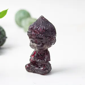 Detail of red translucent resin Sun Wukong figurine in a zen meditation pose on white table
