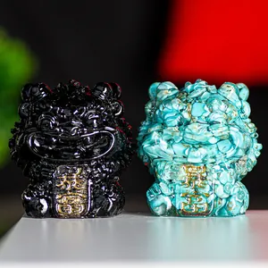 Detail of black and turquoise guardian lion statues with gold prosperity engravings