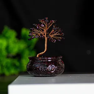 Makroaufnahme vom handgefertigten Geldbaum mit dunkelroten Kristallblättern und Golddraht