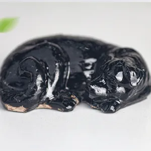 Detail of a high-gloss black Labrador resin figurine sleeping on a minimalist surface