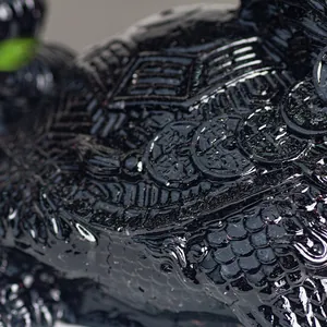 Macro shot of black resin dragon turtle statue with intricate scales and coin details
