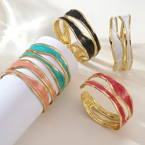 Unregelmäßige goldene Wellenarmreifen mit buntem Emaille-Tropföl im minimalistischen Stil
