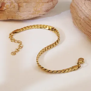 Dettaglio del bracciale a catena cubana dorata con chiusura a moschettone su sfondo di pietra