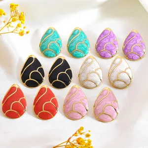 Detail of drop-shaped gold earrings in six assorted enamel colors on white fabric