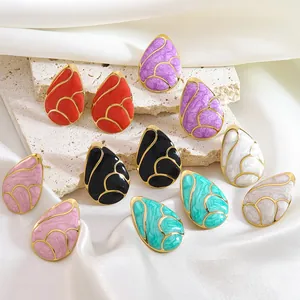 Detailed close-up of colorful teardrop earrings on marble and satin textures