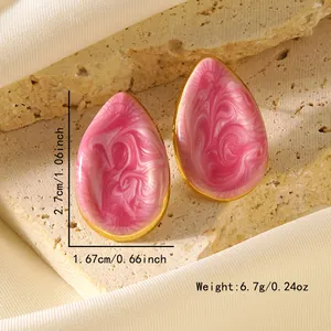 Détail de boucles d'oreilles gouttes en résine marbrée rose et blanc sur socle doré