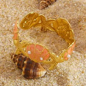Detail van gouden armband in strandstijl met zeester-, schelp- en parelelementen