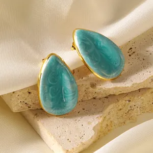 Vue détaillée de boucles d'oreilles goutte avec émail bleu ciel sur un socle