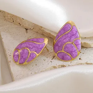 Golden drop earrings with purple marble texture on a luxury silk and stone background