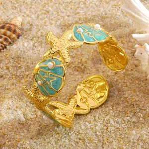 Detail van gouden zeester en schelparmband met parels op echt strandzand