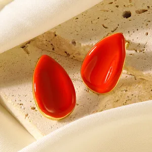 Boucles d'oreilles élégantes en forme de goutte rouge et or sur fond de pierre