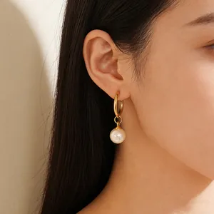 Élégantes boucles d'oreilles créoles dorées avec perles blanches portées par un mannequin