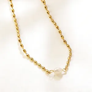 Détail d'un collier de perles dorées avec une perle blanche en forme de goutte d'eau