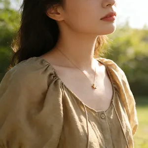 Polished gold star pendant necklace for women worn by a model in a natural outdoor setting