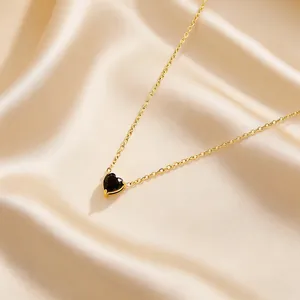 Close-up of heart-shaped black stone pendant with gold chain on champagne silk