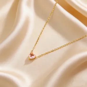 Detail of pink heart birthstone necklace with gold chain on a beige satin background