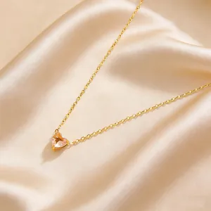 Detailed close-up of golden heart necklace with pink stone on champagne satin