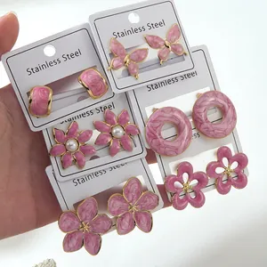 Detailed close-up of pink enamel floral and butterfly stainless steel stud earrings set