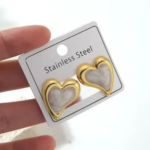 Macro detail of heart-shaped stainless steel earrings with white marble texture inlay