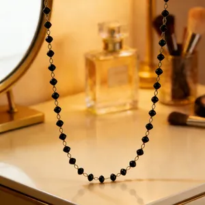 Close-up of elegant black beaded necklace with golden chain link on dressing table