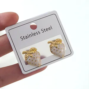 Detailed macro view of strawberry-shaped stainless steel stud earrings with pink enamel finish