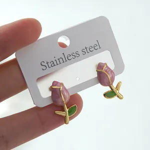 Detailed macro view of tulip stud earrings with pink purple enamel and gold leaves