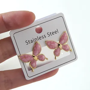 Detailed macro view of pink marble texture butterfly earrings with gold-plated stainless steel edges