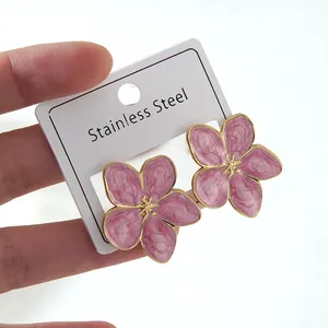 Detailed close-up of pink enamel floral earrings on a stainless steel jewelry card