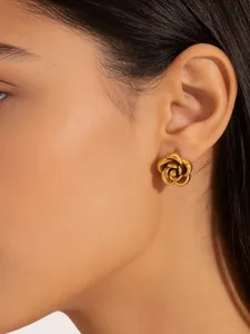 Macro view of gold rose flower stud earrings with a 3D layered petal design on ear