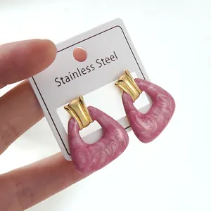 Detail of pink marble resin trapezoid pendants on gold stainless steel earrings