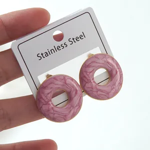 Detailed close-up of pink marble pattern donut earrings with gold-plated stainless steel edges