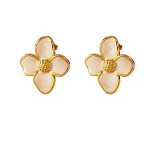 Elegant gold-tone four-petal flower stud earrings with white enamel finish on white background