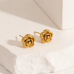 Close-up of matte gold rose stud earrings featuring layered petals on stone block