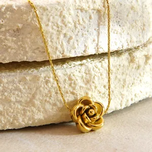 Golden rose pendant necklace and earrings set on natural stone background display