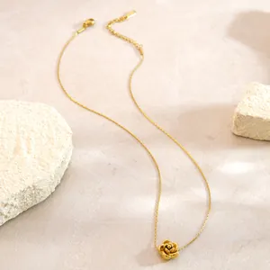 Detail of a vintage 3D gold rose pendant necklace with a fine braided chain