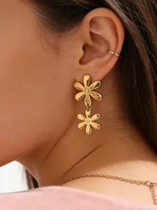 Detail of 18k gold daisy earrings and necklace set worn on a model with a soft pink sweater