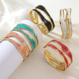 Vista dettagliata di bracciali aperti smaltati ondulati in cinque colori su espositore