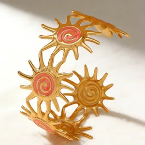 Detailed macro shot of vintage gold sun cuff with colorful pink enamel spiral design